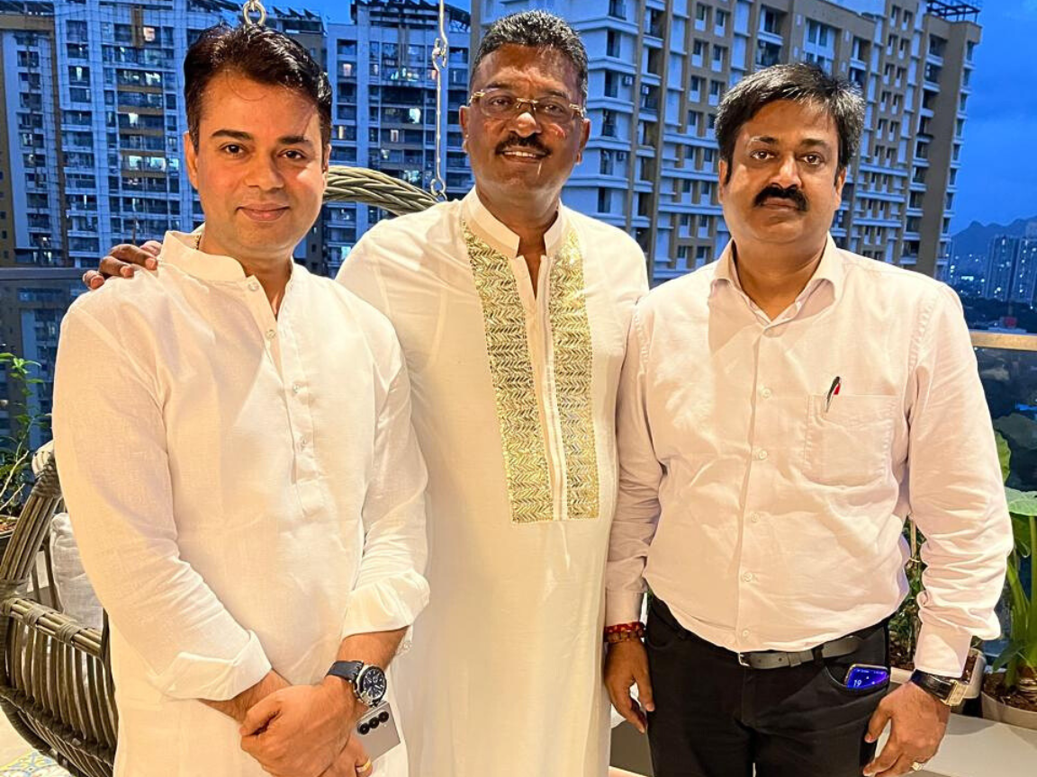 Sunil Keshary stands on the right, Partap Sarnaik is in the center wearing a cream-colored traditional kurta, and Sankar Jha is on the left, with all three posing together in front of a cityscape background.